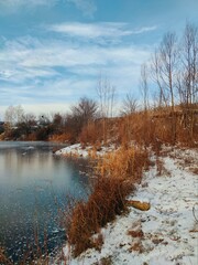 frozen water surface near the shore of the lake against the blue sky in the autumn landscape