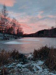 frozen pond near the forest against the background of sunset in the evening landscape