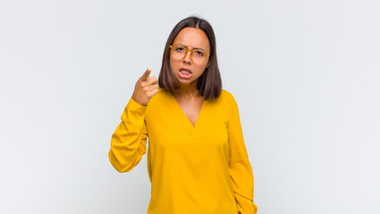 latin woman pointing at camera with an angry aggressive expression looking like a furious, crazy...
