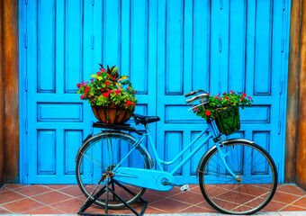 Fototapeta na wymiar Decorative blue vintage bicycle decorated with flower pots on the street of city