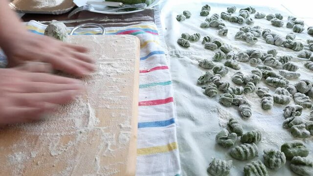 Real time video of female hands making raw spinach and potato gnocchi. Fresch green homemade italian dough dumplings on a towel.