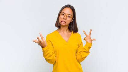 latin woman shrugging with a dumb, crazy, confused, puzzled expression, feeling annoyed and clueless
