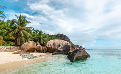 Fototapeta premium Waterfront view at beautiful tropical coast with granite boulders, tropical palms and turquoise water