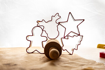 Red gingerbread shapes on a dough roll with a light background and brown baking paper.
