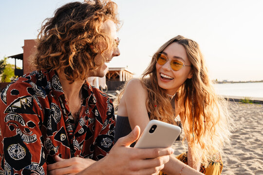 Smiling young loving couple using mobile phone