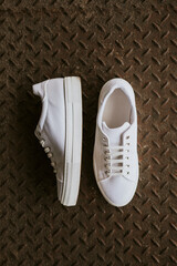 Fototapeta premium White canvas sneakers on metal texture