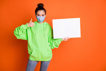 Full size portrait of student show thumb up arm hold placard wear green pullover isolated on orange...