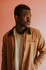 Obraz premium Black man in brown jacket mockup on pink background studio shot