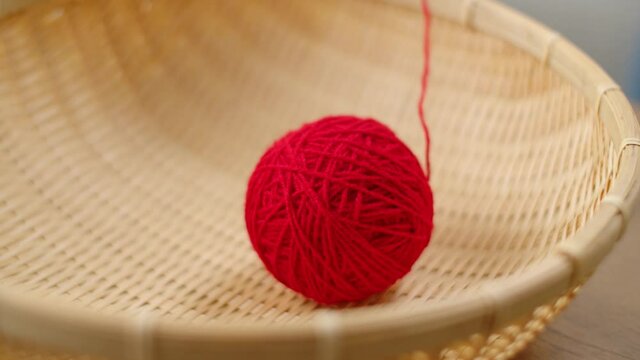 The red ball of thread in the basket unwinds and jumps.