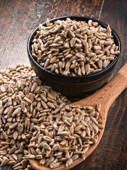 Composition with bowl of shelled sunflower seeds on wooden table