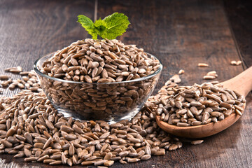 Composition with bowl of shelled sunflower seeds on wooden table