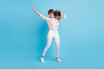 Full size photo of young excited girl crazy have fun enjoy party listen music boombox isolated over blue color background © deagreez