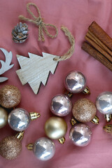 Various Christmas ornaments and cinnamon sticks on pink background. Top view.