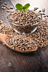 Composition with bowl of shelled sunflower seeds on wooden table