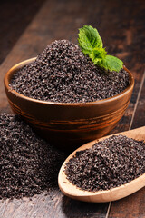Composition with bowl of poppy seeds on wooden table