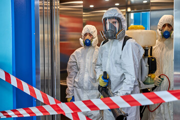 Fototapeta premium people in hazmats making cleaning in apartment building, in prohibited areas. coronavirus concept