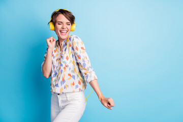 Fototapeta na wymiar Photo of optimistic pretty young woman dace listen headset pop music stand copyspace wear white pants isolated on blue color background