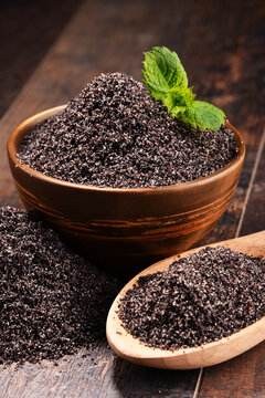 Composition with bowl of poppy seeds on wooden table