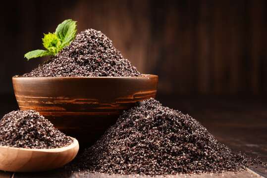Composition with bowl of poppy seeds on wooden table