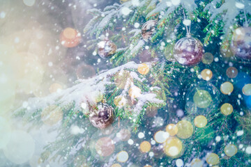Merry Christmas and Happy New Year 2021! Blurred background of Christmas tree in snowfall decorated with silver balls, lights. Forest in snowflakes. Bokeh. Greeting card. Banner. Space for text.