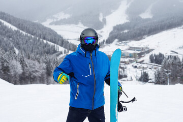 Fototapeta na wymiar Close up portrait guy holding blue snowboard in winter
