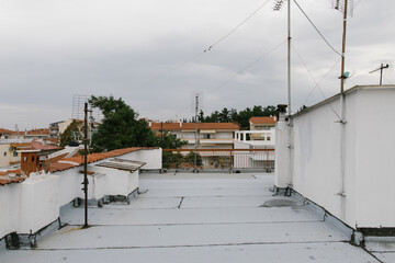 roof top view antenna white building in greece showing buildings across and trees cloudy skies