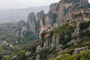 nature mountains and old monasteries buildings trees. cloudy skies europe greece on rock formation edge of cliff