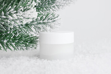 Jar of cream on a white background with a Christmas branch. Container for body care balm. Winter...