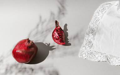 Fresh pomegranates in light on white fabric background.