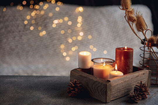Candles in the wooden box isolated on grey white background. Garland lights. The concept of home atmosphere and comfort, holidays, romantic date, winter, home comfort, indoors, Christmas or New Year.