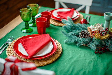 Festive table setting for Christmas dinner at home. Green tablecloth. New Year and Christmas decorations. Winter holiday theme. Happy New Year.