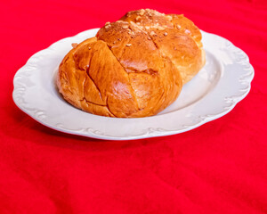 tsoureki, traditional Greek sweet bread served on white plate and red fabric background