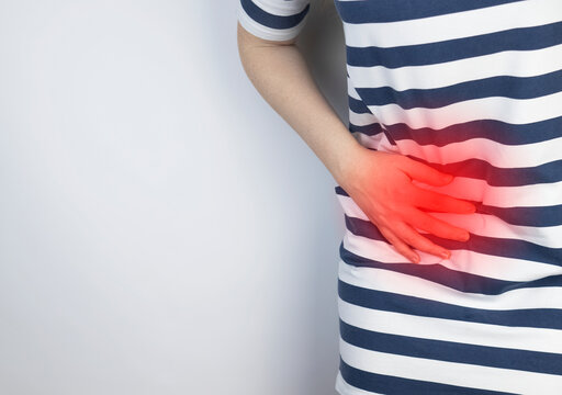 A woman holds on to his stomach. Pain in the abdominal cavity. The concept of diseases of the stomach and digestive system. The doctor will palpate to find out the source of the pain