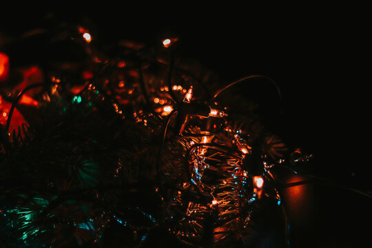 Dark photo with a full range of colored lights on a black background creates a wonderful spirit of the approaching Christmas. Red, orange, blue, green and more. A peaceful Christian holiday.