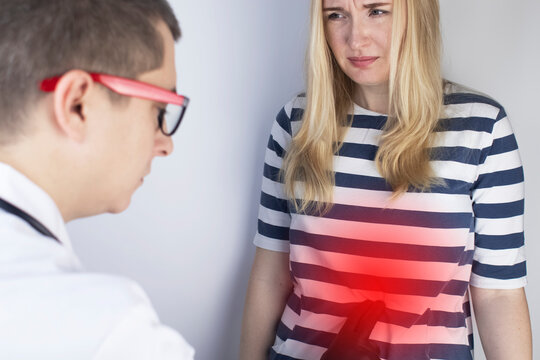 A woman holds on to his stomach. Pain in the abdominal cavity. The concept of diseases of the stomach and digestive system. The doctor will palpate to find out the source of the pain