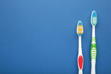 Two toothbrushes on blue background with copy space.