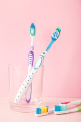 Toothbrushes in glass on pink background tools for oral care