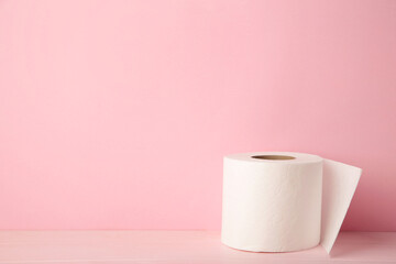 Roll of toilet paper on pink background, top view.