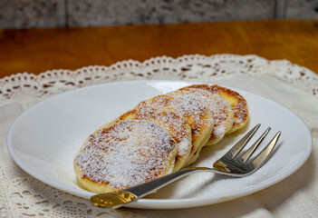 cheese pancakes with powdered sugar on a white plate close-up