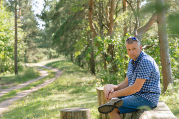 Portrait of a man in the forest. The traveler stopped to rest and sat down by the road