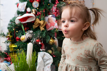 Little girl playing next to Christmas tree and making a secret  wishes to send  to Santa