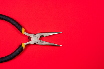 The round nose pliers on the red background of copyspace. For electrician, jeweler and builder....