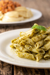 Penne pasta with pesto sauce on rustic wooden table	
