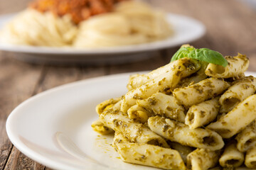 Penne pasta with pesto sauce on rustic wooden table	