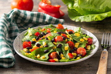 Mexican salad with black beans, corn,tomatoes,lettuce and pepper on wooden table