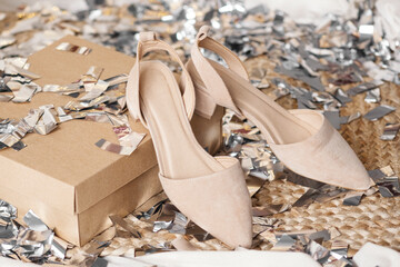 Womens shoes after the celebration stand on a box on the floor against a background of silvery confetti. Beige Slingbacks - womens shoes with a strap. Women's fashion and style