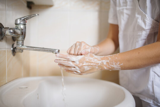 Hands washing. Person washing their hands with soap. Doctor washing hands after the surgery wearing a white lab coat
