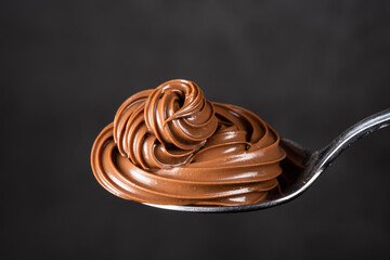 Cream chocolate in spoon on black background	