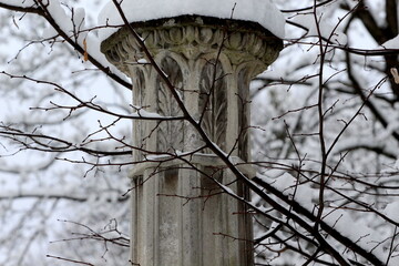 Piękna słoneczna zima. Śnieg na gałązkach.  Fragment rzeźby na cmentarzu Lyczakowskim we Lwowie.