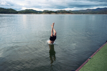 Fototapeta na wymiar Young man diving into lake in dam